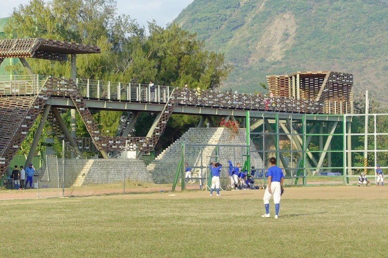 boys playing baseball on a field with several wooden structures above