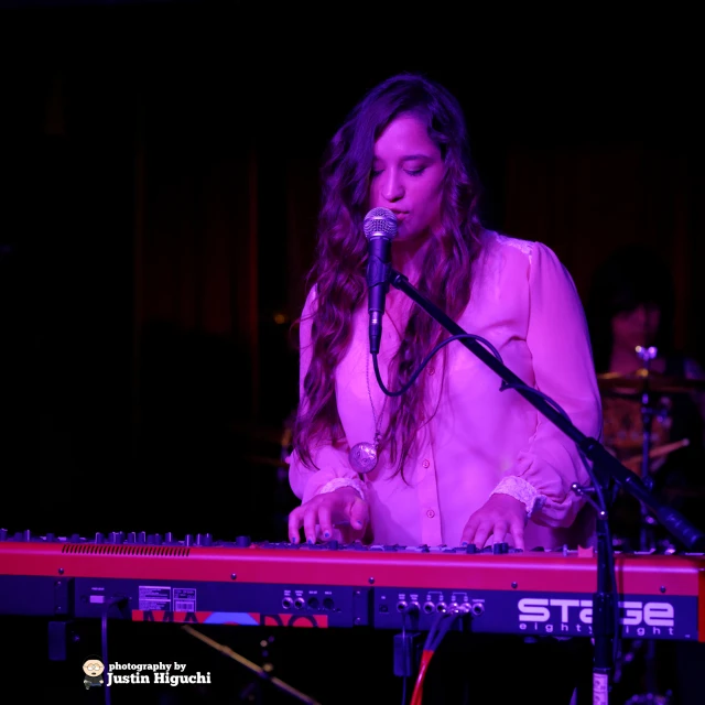 a beautiful young lady standing next to a keyboard