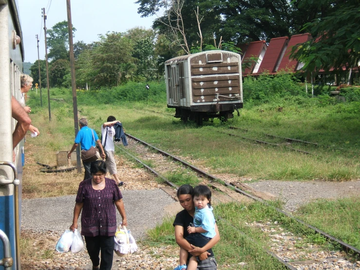 people walk up and down railroad tracks near a trailer