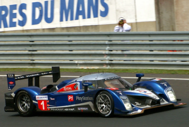 a racing car driving on a track with a person in the background