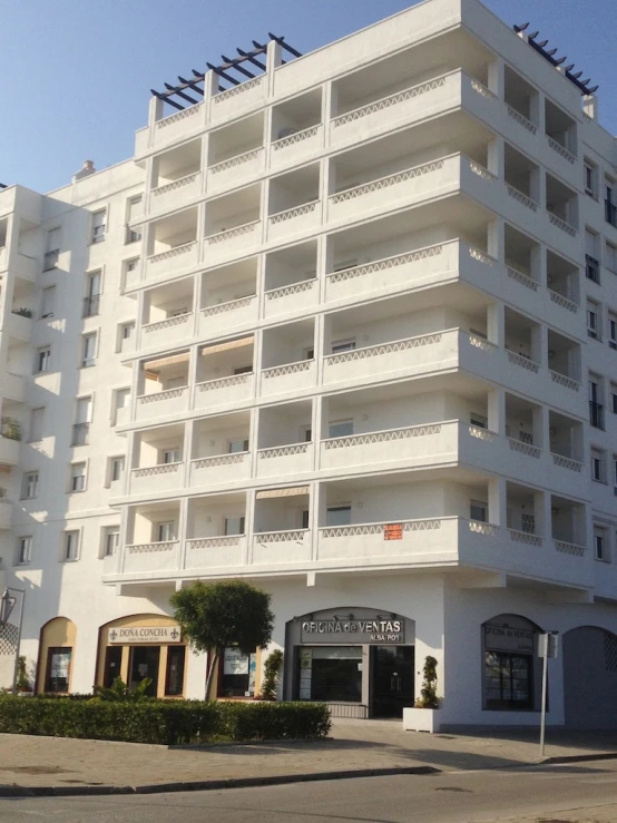 an all white building that has multiple balconies on top