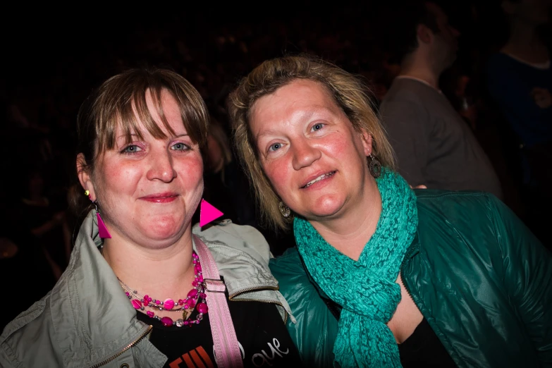 two women are smiling for the camera in front of a crowd