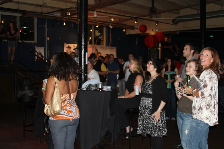 two woman standing at a party and two people are smiling