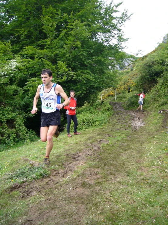 a man is running down a hill near some trees