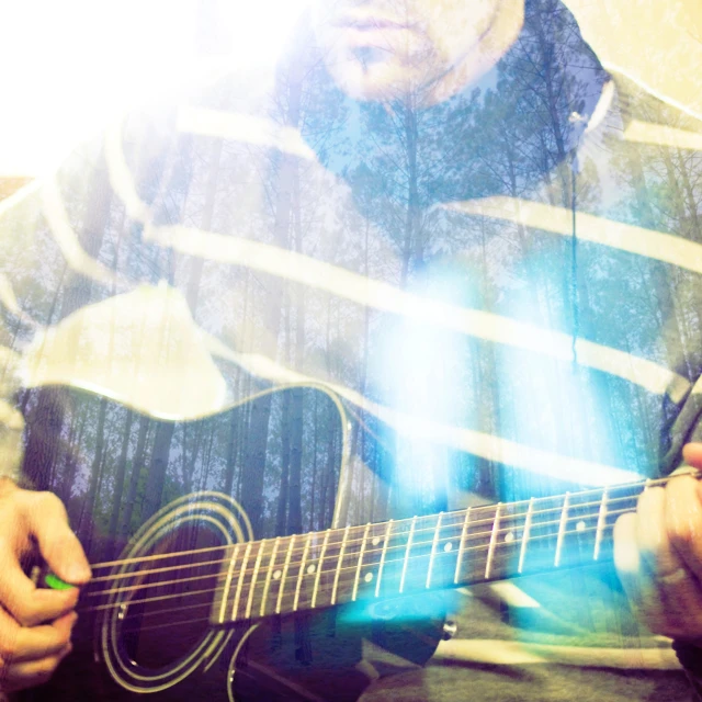 a man playing an acoustic guitar while using his hand to play