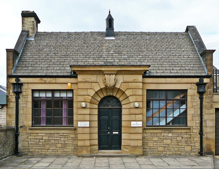 the entrance to a small brick building with a black door and windows