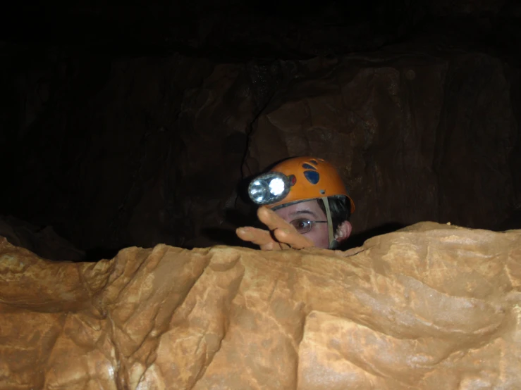 boy holding his head out from inside a cave
