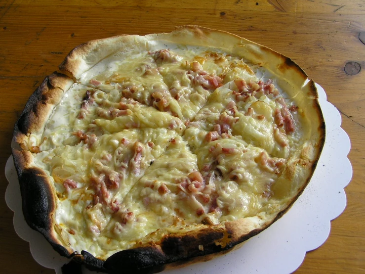 a cheese dish on a white plate with some bacon