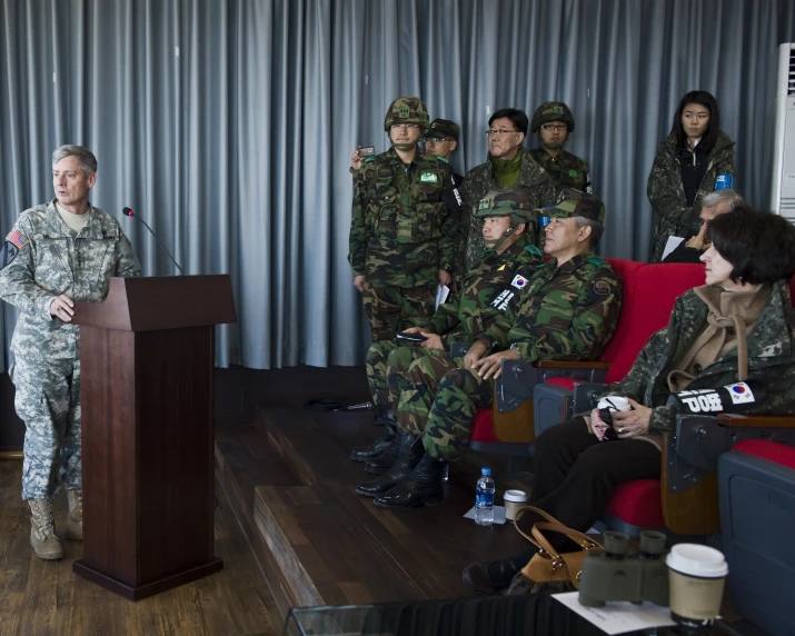 a group of people dressed in military uniforms and holding a microphone are sitting on a red couch