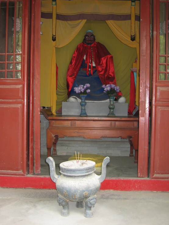 statue with gold scarf in front of red and yellow structure