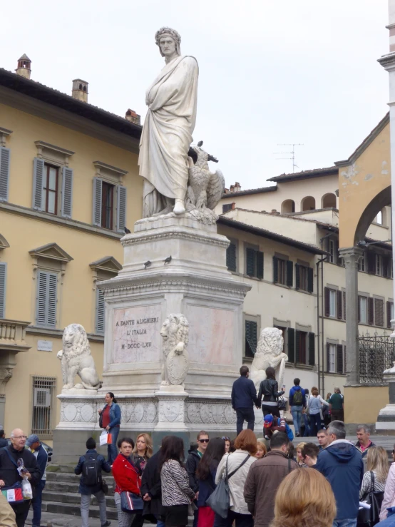 a crowd of people gather around the marble statue