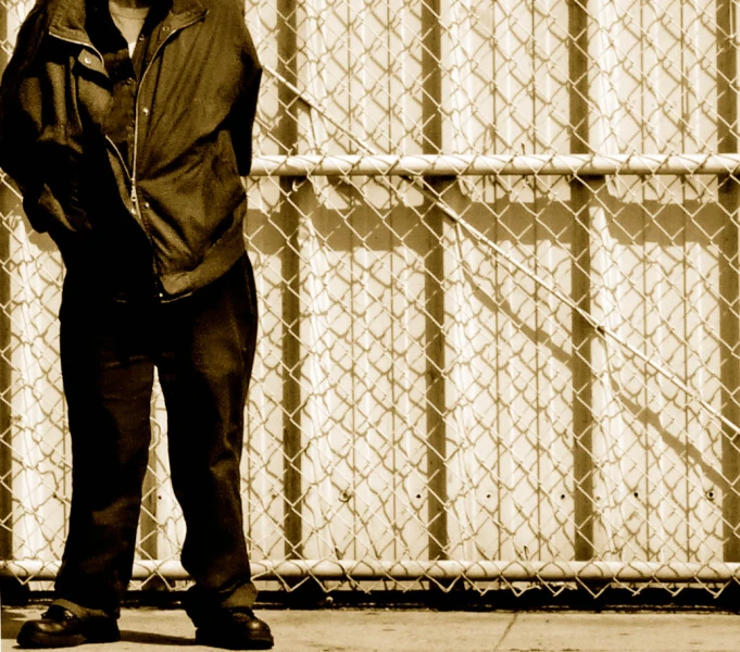 a man that is standing by a fence