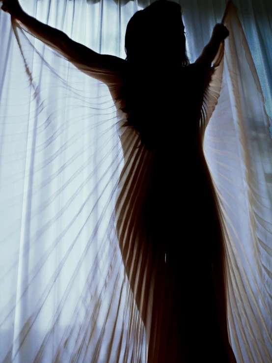 a woman in a dress stands behind a curtain