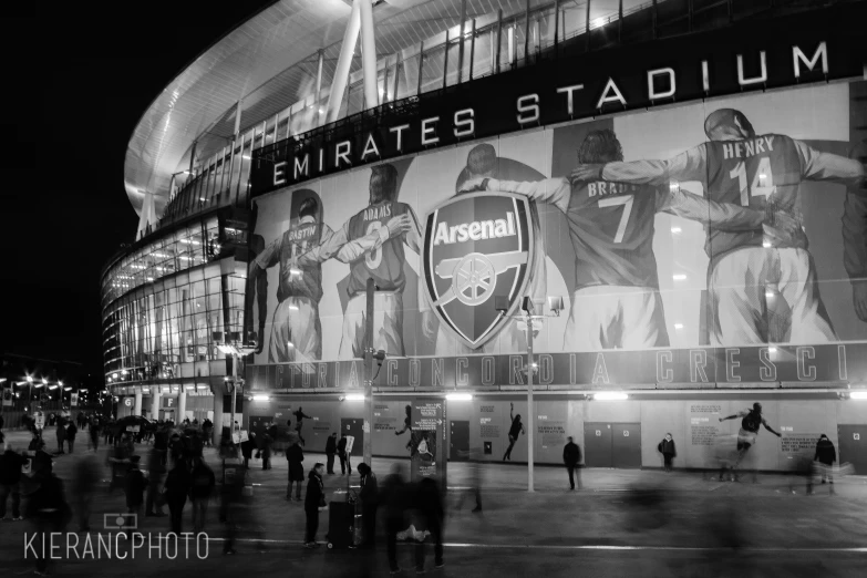 people walking around outside a stadium in the night