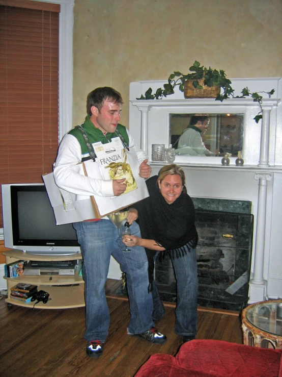 a man and woman in front of a fireplace, one holding a book