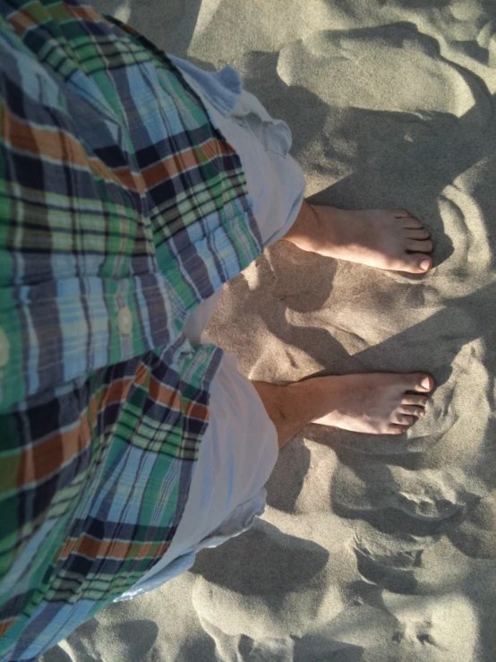 the legs of someone standing on the sand with their shoes on