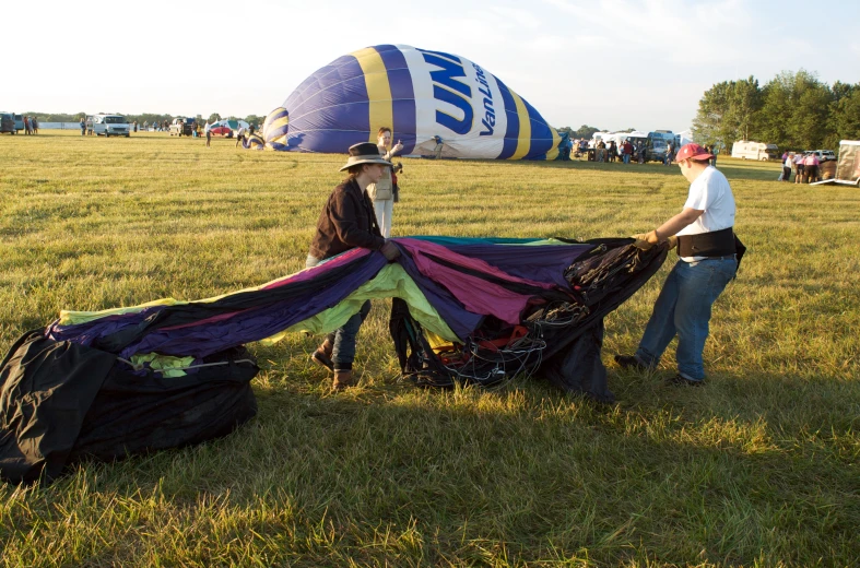 two men standing next to one another in a field with a huge kite