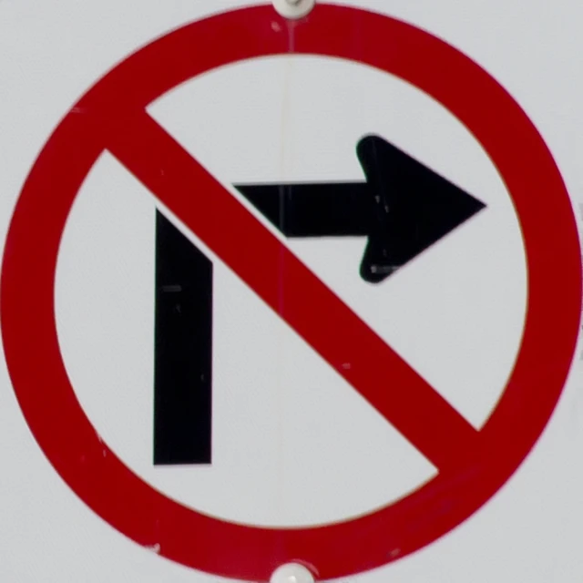 two red no left turns signs in front of a white wall