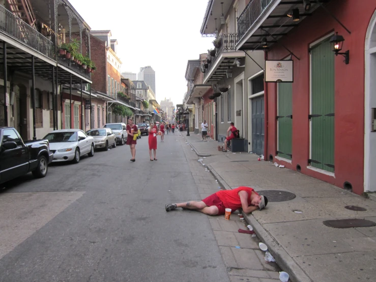 a man laying on the sidewalk near other people