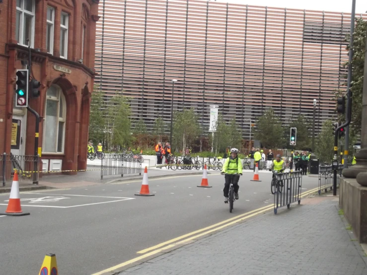 two people riding bikes across a street near construction cones