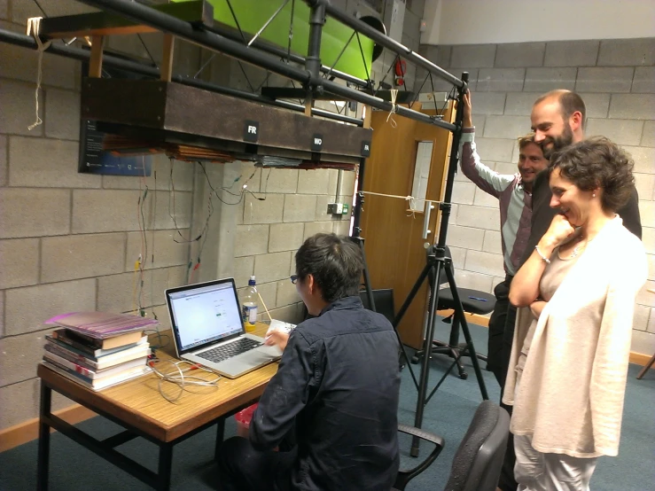 a man standing next to a table while holding a laptop