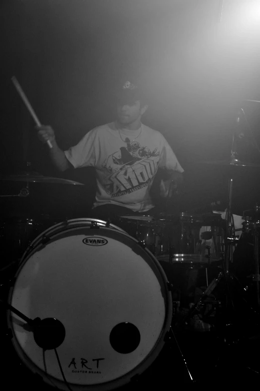 a man with drums plays behind a drum set in a dark room