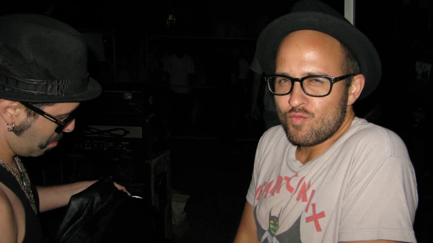 a man wearing glasses and a hat in the dark