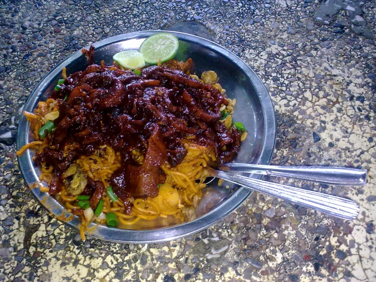 a bowl with a meat mixture and two spoons