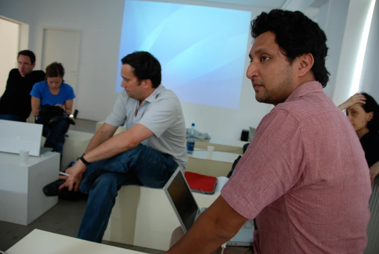 some people sitting and standing in chairs in an office setting