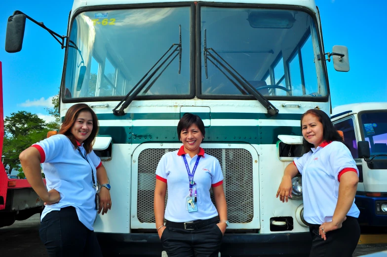 the three women are standing in front of a bus