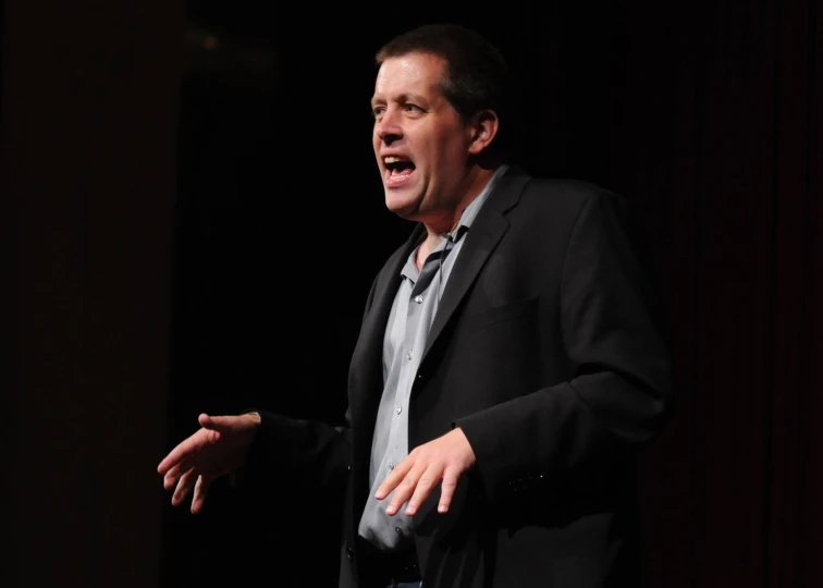 a man in a suit speaks at a seminar