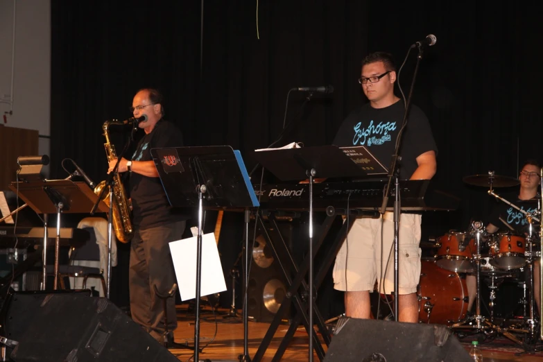 a man standing in front of a keyboard on stage next to another man