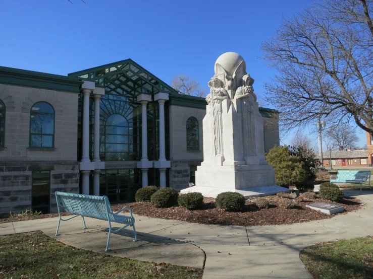 two blue park benches sit next to a statue in front of a building