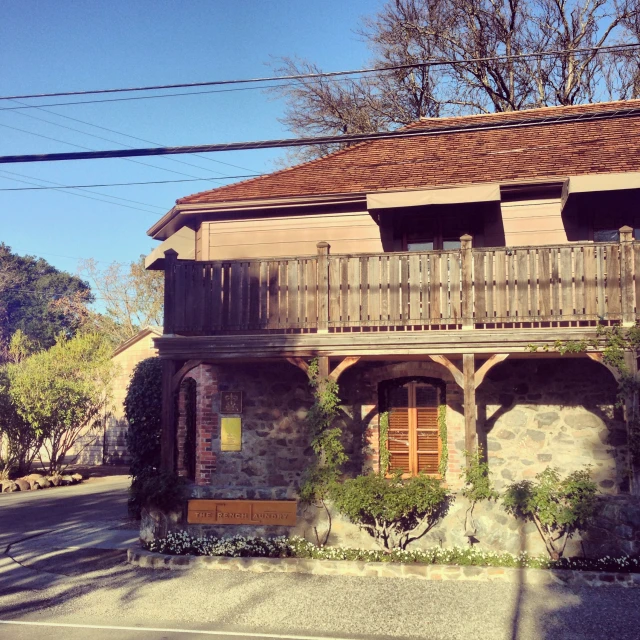 an old stone house has wood balustings on the front and sides