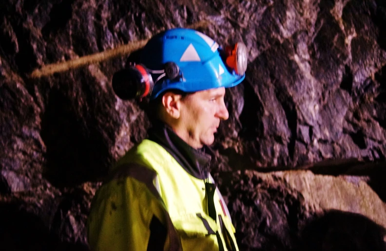 a man in a hard hat looks ahead with a mountain