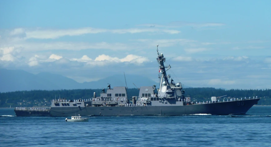 an battleship with a small boat in the background