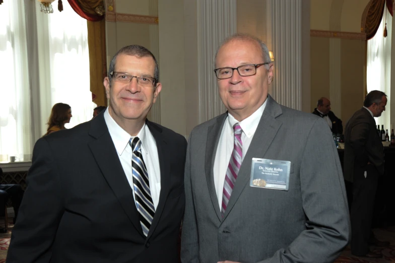 two men posing for a picture together while wearing suits