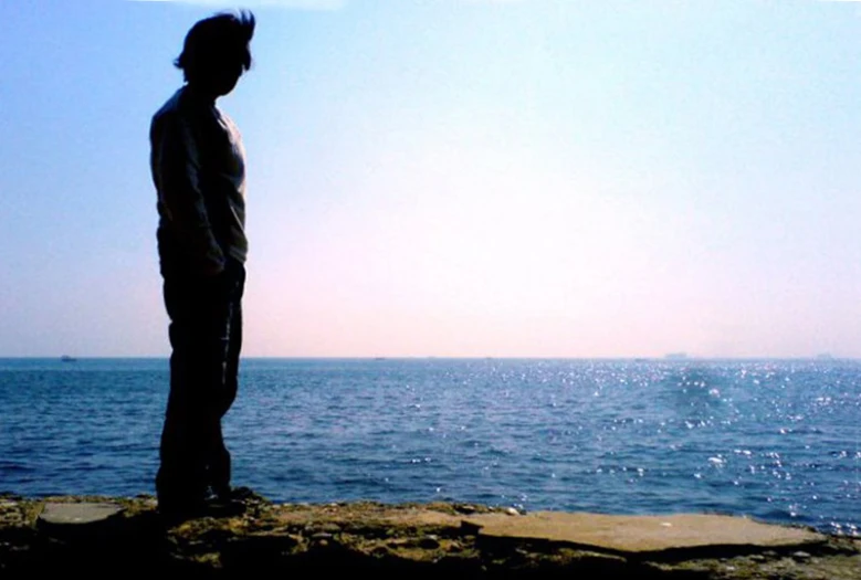 the man stands on a cliff near the ocean