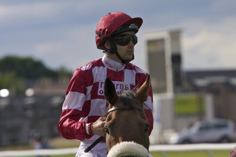 man in red and white jockey outfit riding a horse