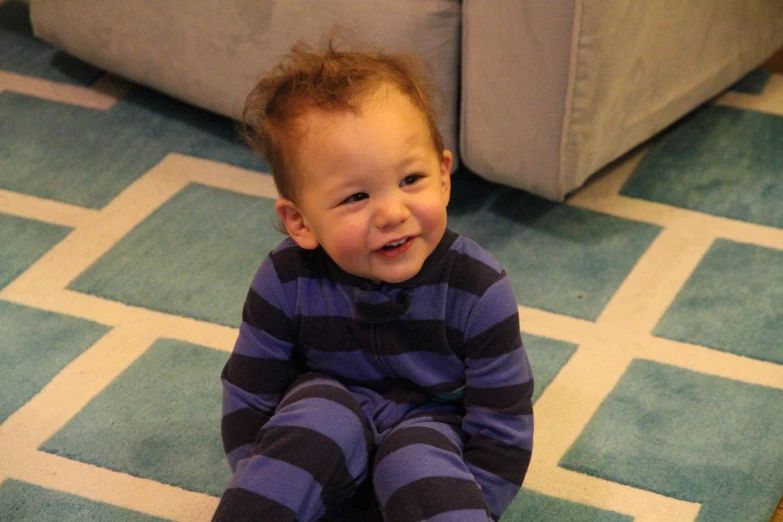 small child wearing a striped blue and purple outfit and smiling