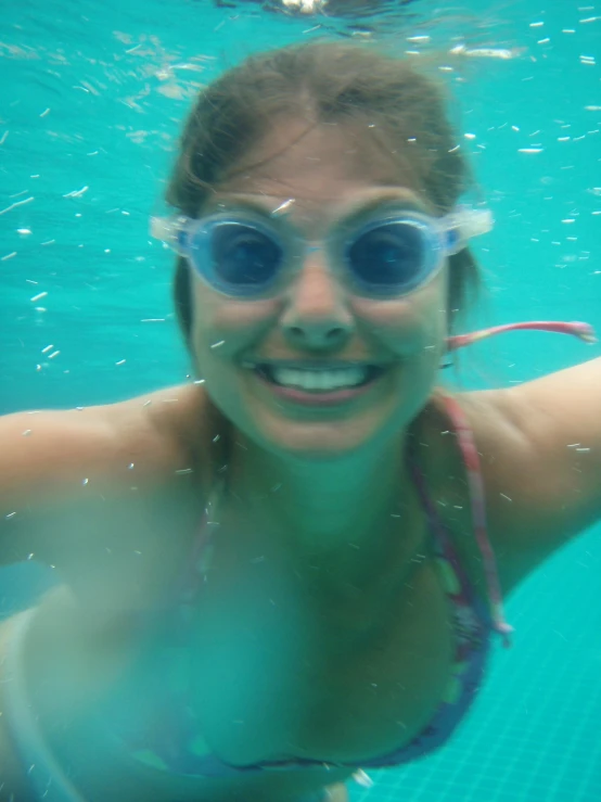 a woman wearing blue goggles under water