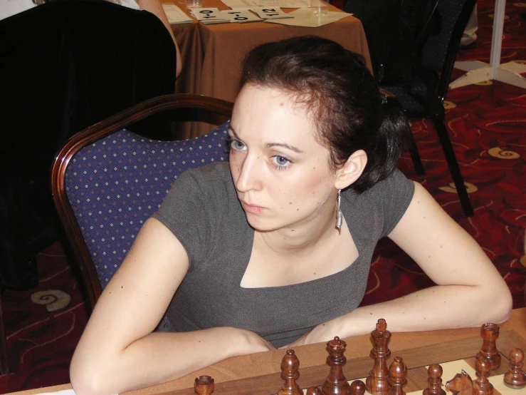 a woman sitting at a table with chess pieces