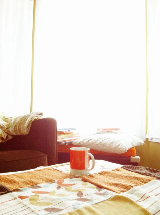 a room with an orange coffee cup on the bed