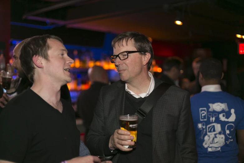 two men talking next to each other with glasses