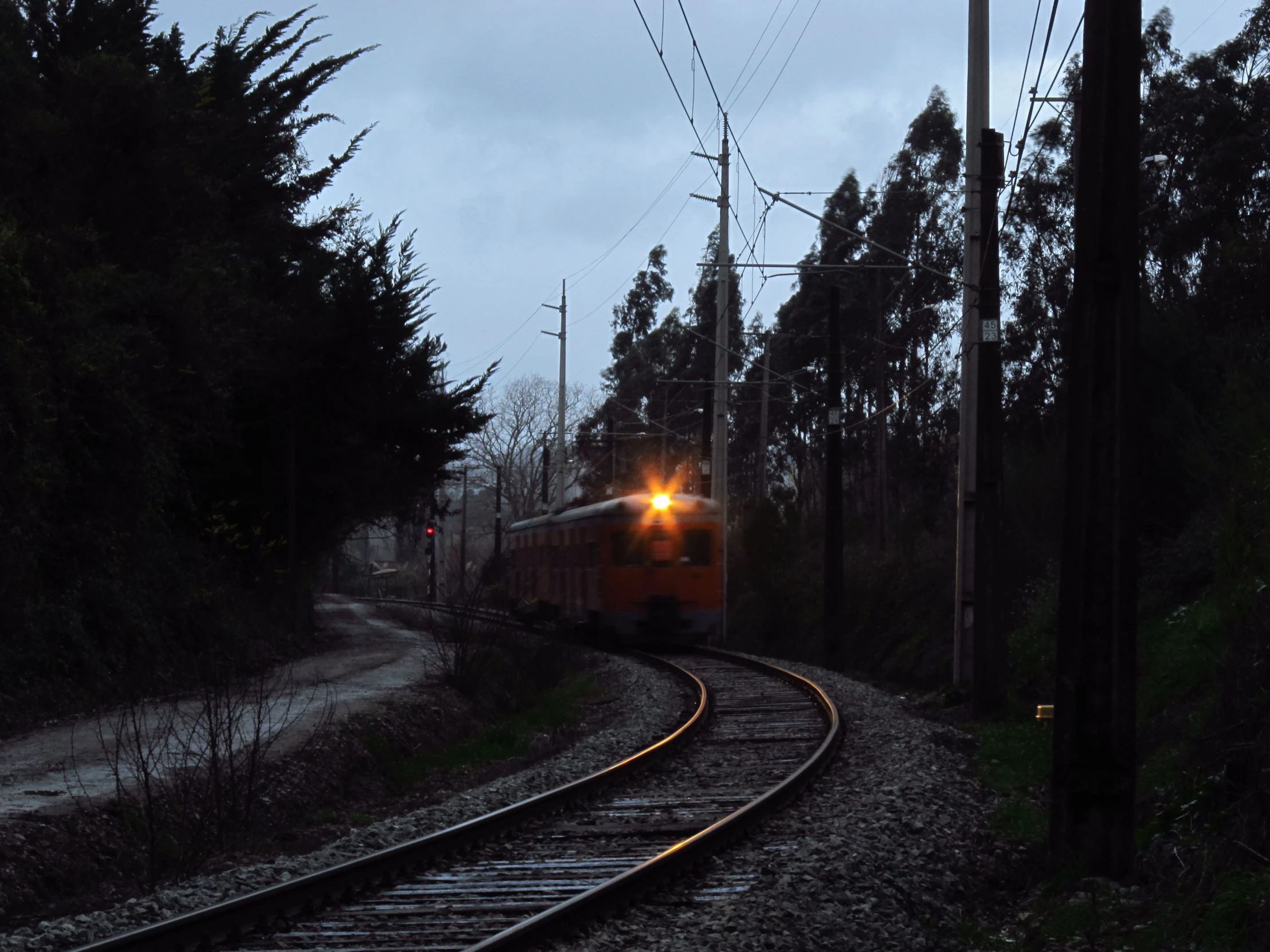 the train is traveling down the tracks as dark comes