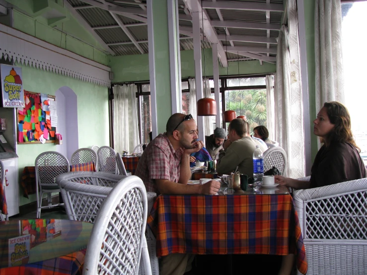 several people sit at tables with their food and drink