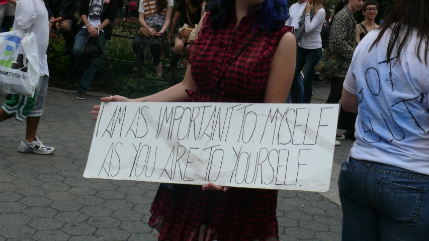 a woman holding up a sign with her left hand