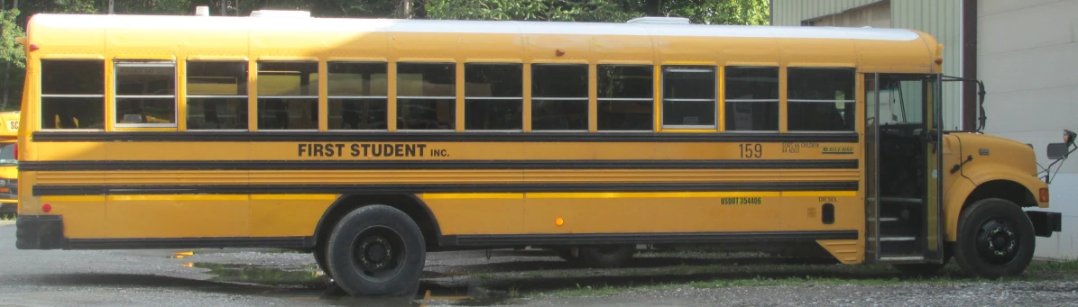 this yellow school bus is parked in the gravel