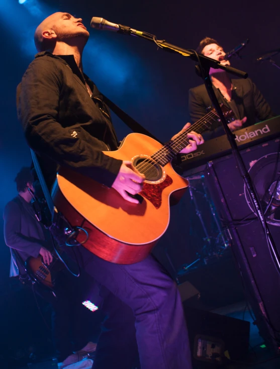 two men with guitars singing into microphones on stage