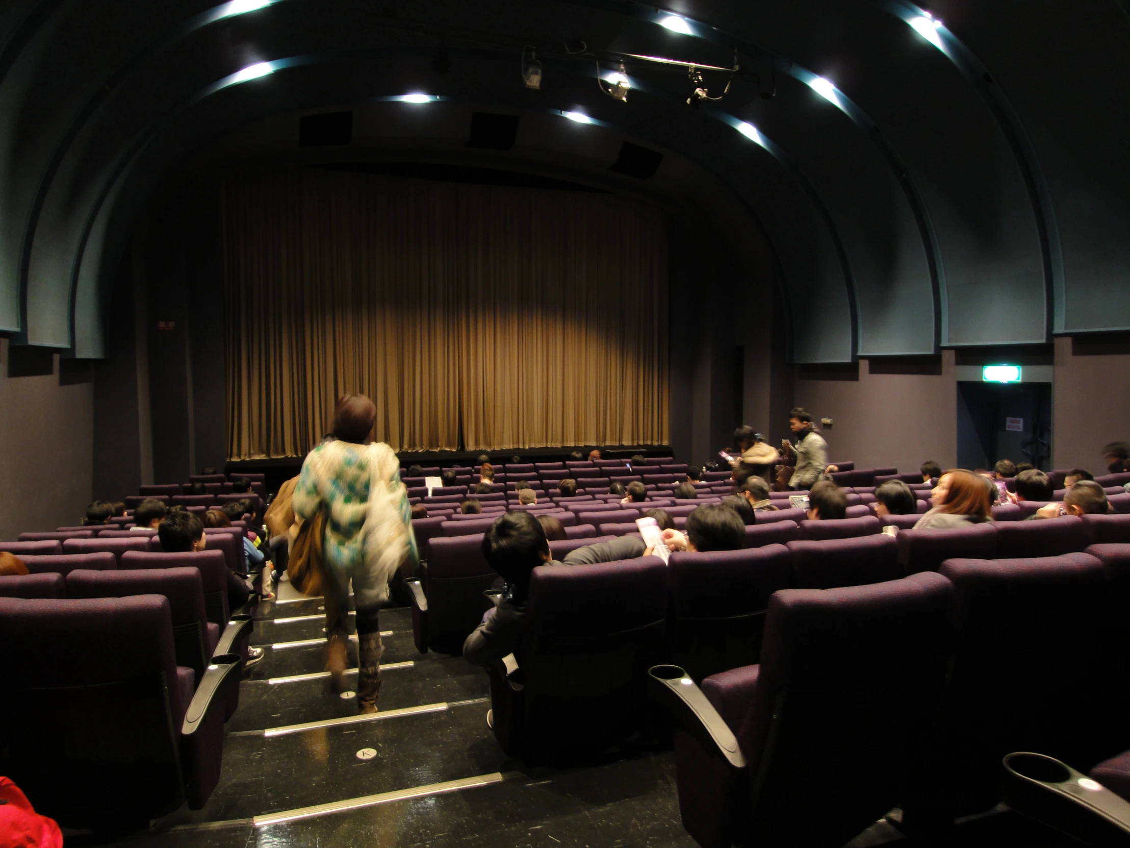 people in chairs and a man walking towards the auditorium stage